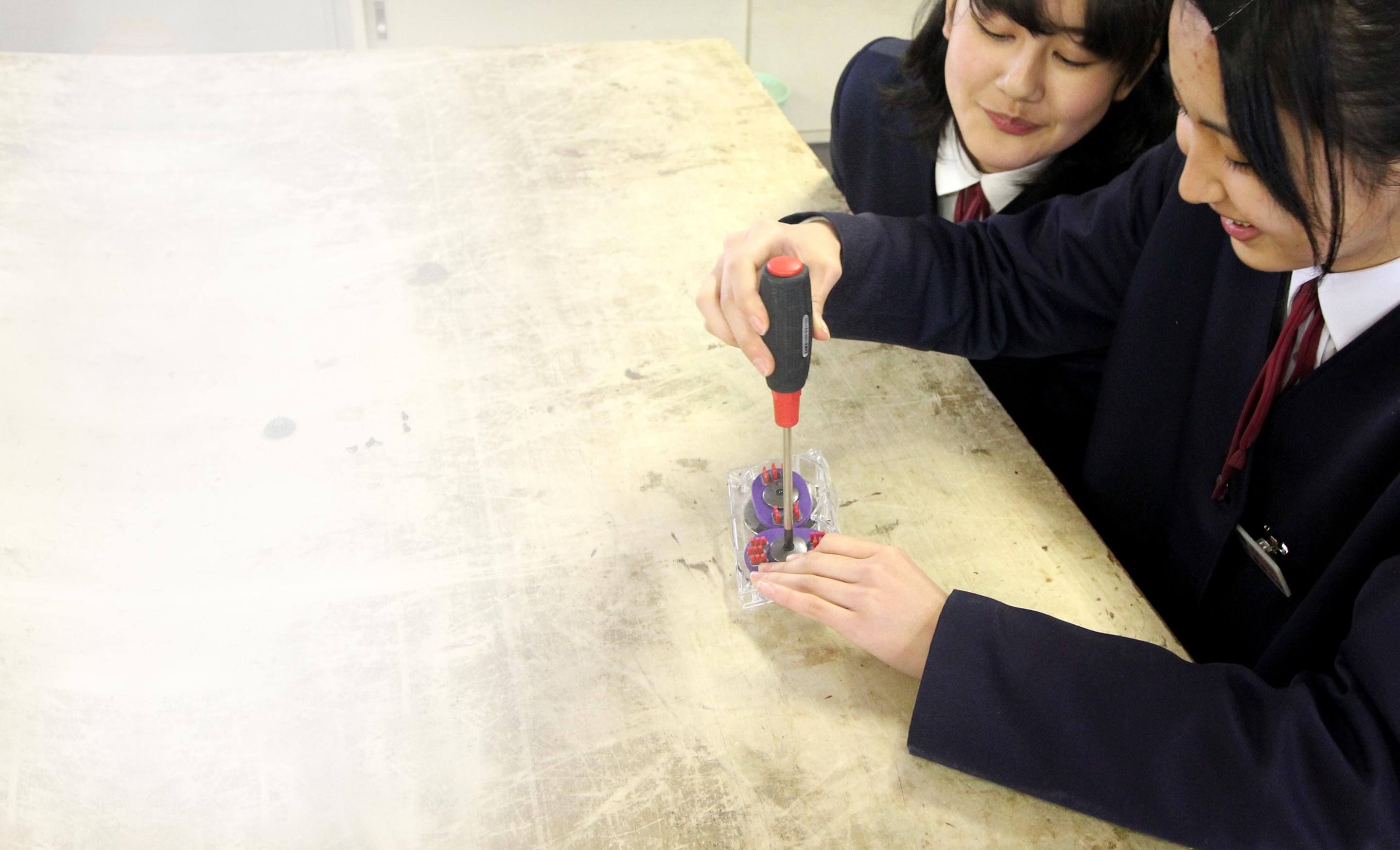 A teacher showing students how to disassemble a Dyson Tangle-free Turbine Tool.